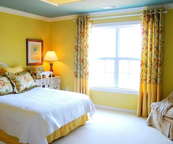 quarto amarelo retro simples a estampa da cortina e as paredes amarelas remetem a quartos dos anos 60 e 70
