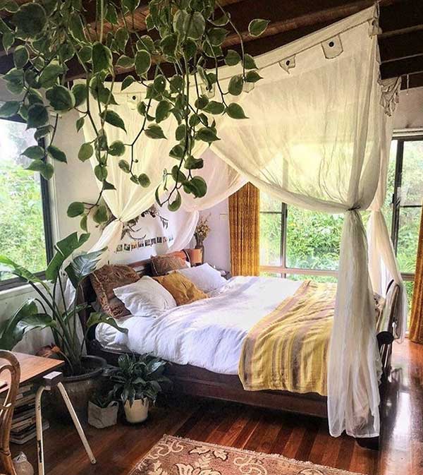 quarto boho casal para o casal, cortinas em volta da cama, plantas e luz natural vão acentuar a intimidade e aumentar o relaxamento