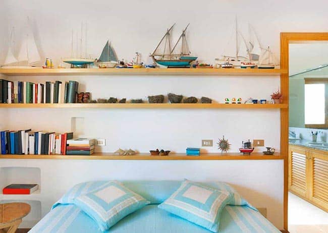 Prateleiras de madeira com barcos para decoração de um quarto masculino.